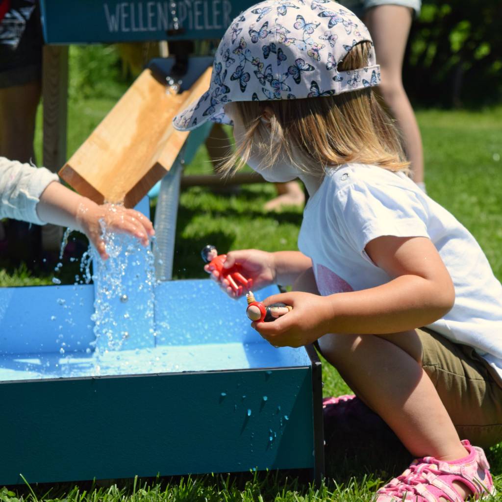 Kleines Mädchen spielt am WELLENSPIELER Wasserspiel Bodenbecken
