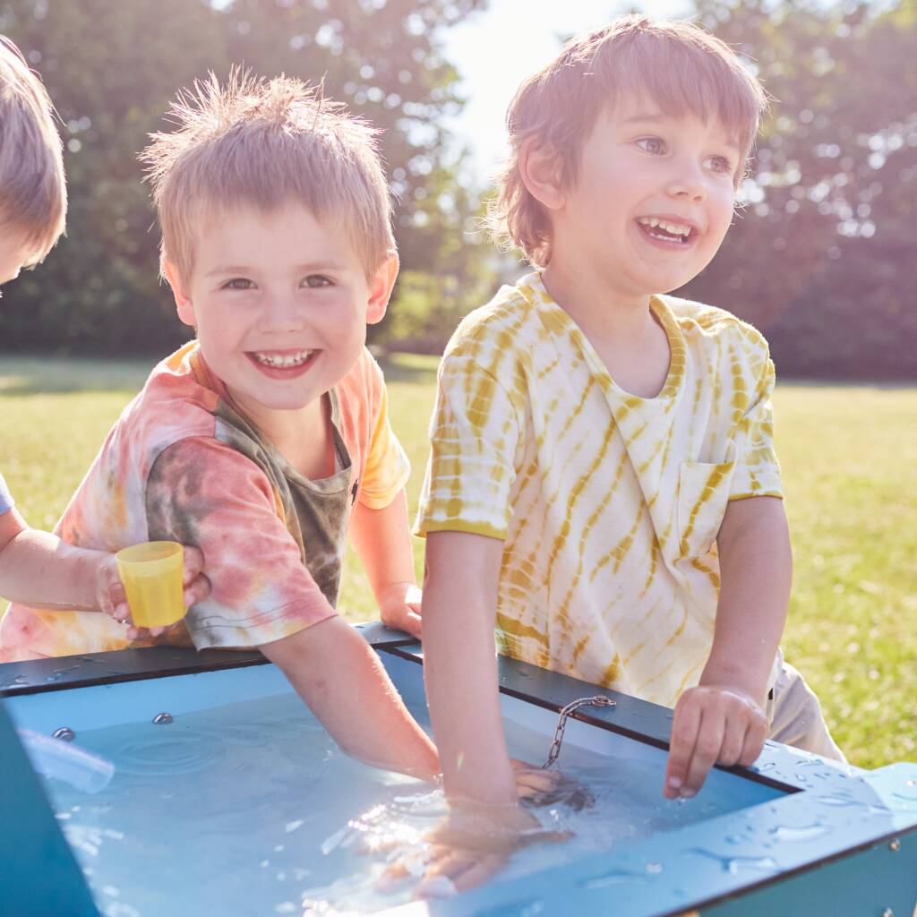 Kinder spielen mit Wasser an der mobilen Wasserspielanlage in der Kita.