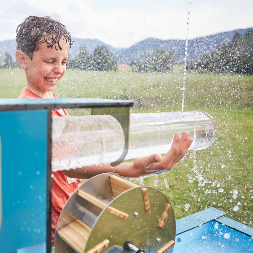 Kind spielt an einem mobilen Wasserspielgerät in der Kita.
